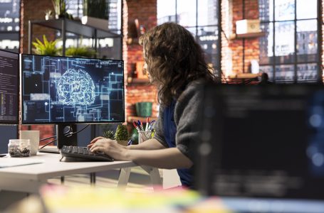 Teleworking developer using computer for artificial intelligence computing through self learning algorithms. Agency IT engineer works with AI deep neural networks on desktop PC.