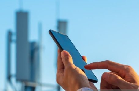 5G communications tower with man using mobile phone